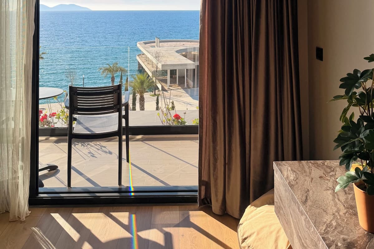 Une pièce dotée d’une grande porte-fenêtre coulissante donnant sur un balcon avec vue sur la mer et un immeuble.