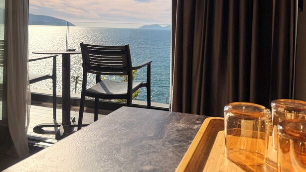 A room with a view of the sea, a table with glasses, and a chair. - Esbjerg Hotel (Vlorë)