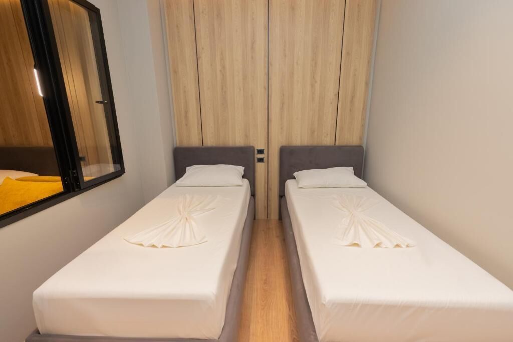 Ein Zimmer mit zwei Einzelbetten, einem Holzschrank und einem Spiegel.