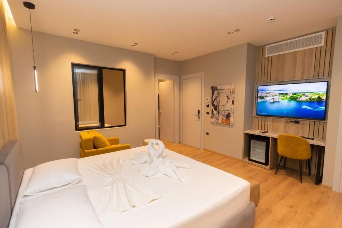 Une chambre d’hôtel avec un lit, un bureau, une télévision et une chaise.