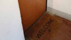 Una puerta de madera con un felpudo que dice 'WELCOME'.