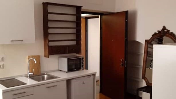 Una cocina compacta con armarios blancos, un microondas y un fregadero.