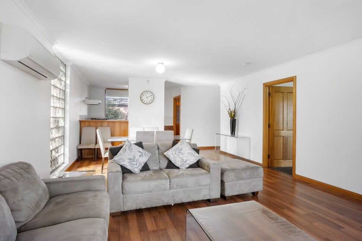 A living room with a sofa, a coffee table, and a dining area with chairs and a table.