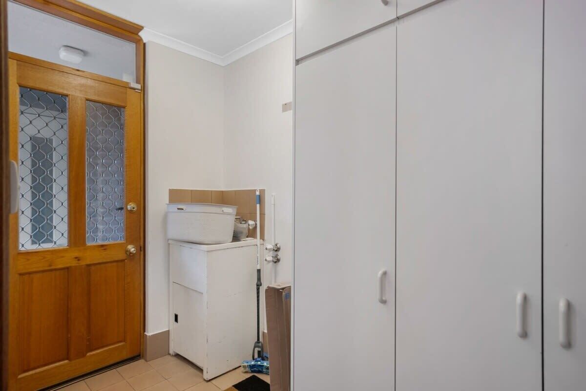 A room with a wooden door, a white washing machine, and a white wardrobe.