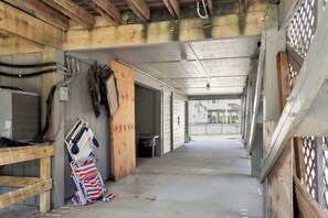 Een gang met zichtbare houten balken, een rolstoel en een betonnen vloer.