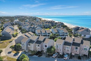 A coastal residential area with multi-story buildings, a beach, and clear skies.