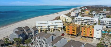 A coastal residential area with beachfront properties, including multi-story buildings and a sandy beach.
