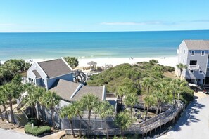 A beachfront property with a large house, a covered patio, and a view of the ocean.
