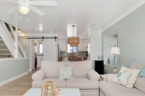 A modern living room with a sofa, a coffee table, and a dining area with a table and chairs.