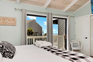 A bedroom with a bed, a chair, and a view of the outside.