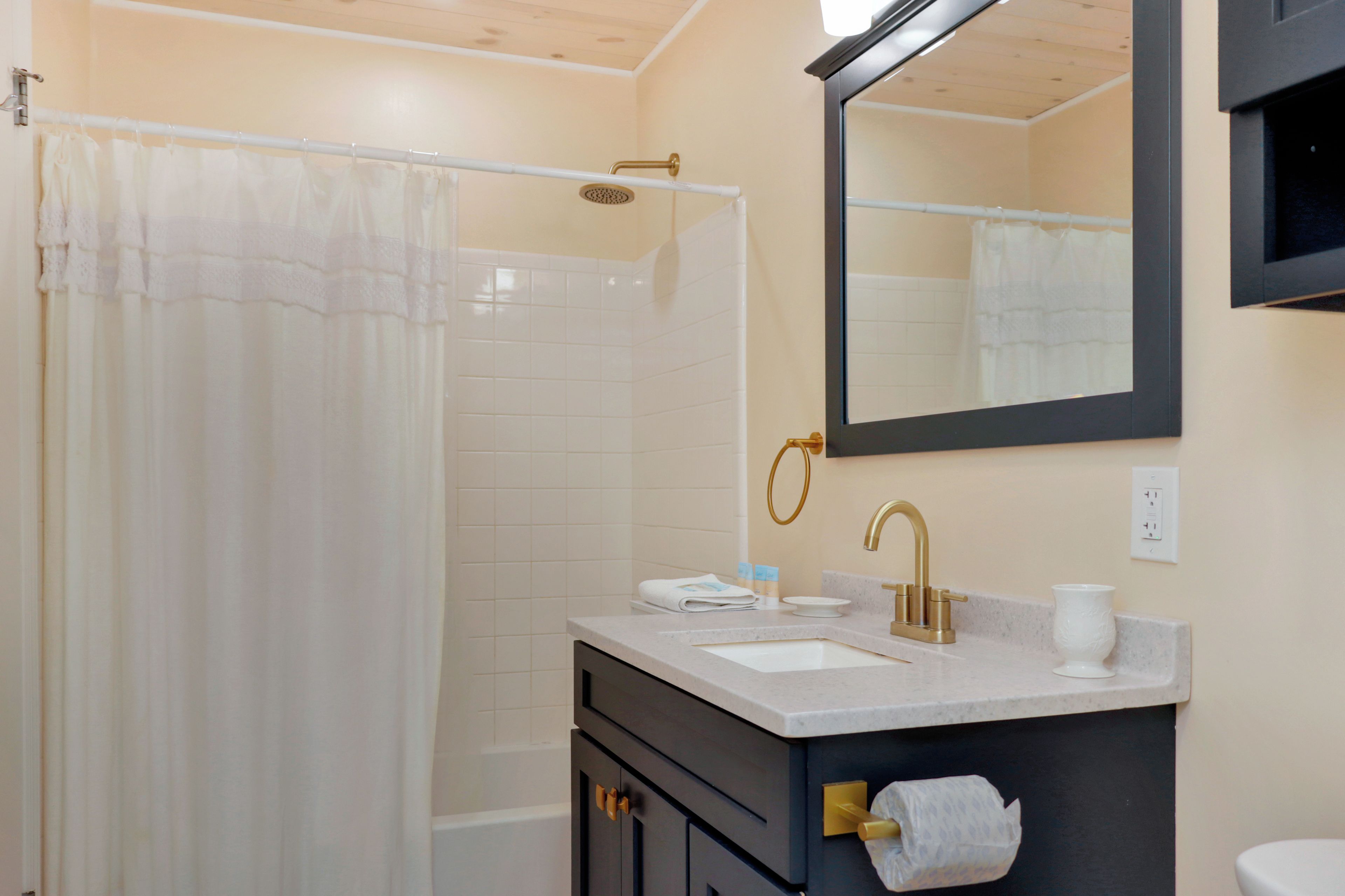 A bathroom with a shower, a sink, a mirror, and a toilet.