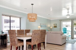 Un coin repas avec une table et des chaises, un luminaire suspendu et un canapé en arrière-plan.
