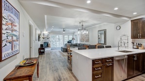 A modern kitchen with a large island, wooden cabinets, and a dining area with a sofa and chairs. - Modern and Updated St James Premium 3 Bedroom Residence 3 Condo by RedAwning (Avon)