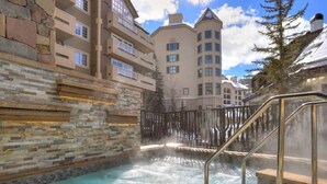 A spa area with a hot tub surrounded by stone walls and a metal railing. - Luxury 4 bedroom Premier Residence at St James Place 4 Condo by RedAwning (Avon)