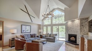 A spacious living room with a fireplace, large windows, and a high ceiling. - Luxury 4 bedroom Premier Residence at St James Place 4 Condo by RedAwning (Avon)