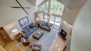 A spacious living room with a large window, a fireplace, and a modern chandelier. - Luxury 4 bedroom Premier Residence at St James Place 4 Condo by RedAwning (Avon)