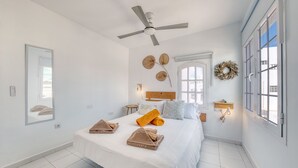 A hotel room with a bed, ceiling fan, large windows, and a view of the outside. - Chez Carmen • Pool View • Beach 900M • LVH (Puerto del Carmen)