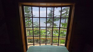 A room with a large window offering a view of a lake and trees. - Charming 4-Bedroom Linekin Log Cabin in Boothbay, ME with stunning waterfront views. (Boothbay)