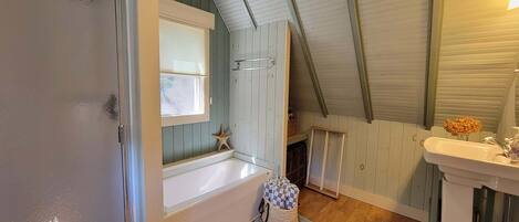 Une salle de bain avec une baignoire, une fenêtre, un élément de décoration en forme d’étoile de mer et un lavabo.