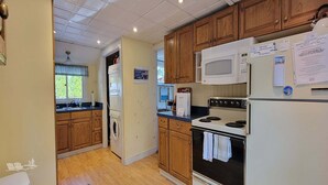 A kitchen with wooden cabinets, a microwave, a stove, and a refrigerator. - Experience lakeside luxury at Piffi Biff, a spacious 5-bedroom cabin on Southport, ME. (Southport)