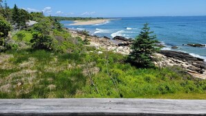 A coastal landscape with a rocky shoreline, dense greenery, and a clear blue sky. - Your Tranquil Indian Point Retreat with Breathtaking Views & Beach Access (Georgetown)