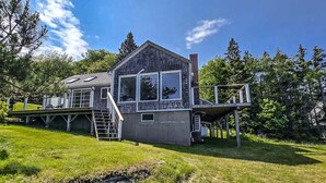 A house with a deck, a chimney, and a large window. - Your Tranquil Indian Point Retreat with Breathtaking Views & Beach Access (Georgetown)