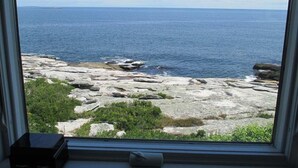 A view through a window of a rocky coastline with the sea in the background.