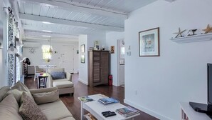 Un soggiorno con divano, tavolino e televisore. Sullo sfondo, una zona pranzo con tavolo e sedie.