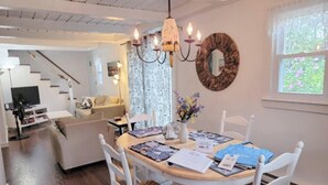 Zona pranzo con tavolo rotondo, sedie e lampadario.