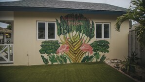 Um edifício com um mural de plantas tropicais e flamingos, e o texto "Almost Heaven Aruba".