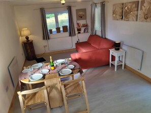 Cozy living space with a dining area and seating area, featuring a dining table, sofa, and side table with a lamp.