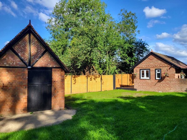 Traditional home with a gabled roof and attached shed, set amidst a well-maintained lawn and enclosed yard.