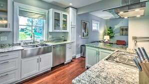 Una cocina moderna con gabinetes blancos, un lavamanos de acero inoxidable y una encimera de granito.