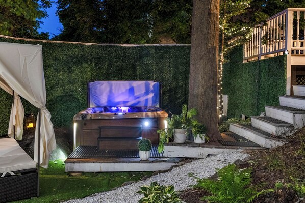 A hot tub with a blue light, surrounded by a hedge, steps, and a tree. - Hot Tub + Walk to Lakeside Dining: Meredith Home! (Meredith)
