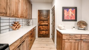 A kitchen with wooden cabinets, a tiled backsplash, and a door leading to another room. - Blue River Flats Retreat: Stunning Getaway With Amazing Views (Silverthorne)