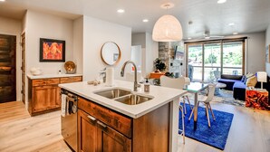 A modern kitchen with a central island, wooden cabinets, and a large window. - Blue River Flats Retreat: Stunning Getaway With Amazing Views (Silverthorne)