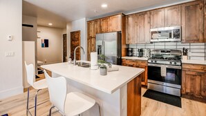 A modern kitchen with wooden cabinets, stainless steel appliances, and a central island with seating. - Blue River Flats Retreat: Stunning Getaway With Amazing Views (Silverthorne)