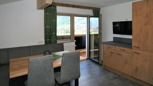A modern kitchen with a wooden countertop, a built-in TV, and a sliding glass door leading to a balcony. - Panoramablick by Interhome (Mayrhofen)