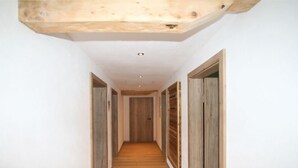 A narrow hallway with wooden flooring and wooden doors on both sides. - Panoramablick by Interhome (Mayrhofen)