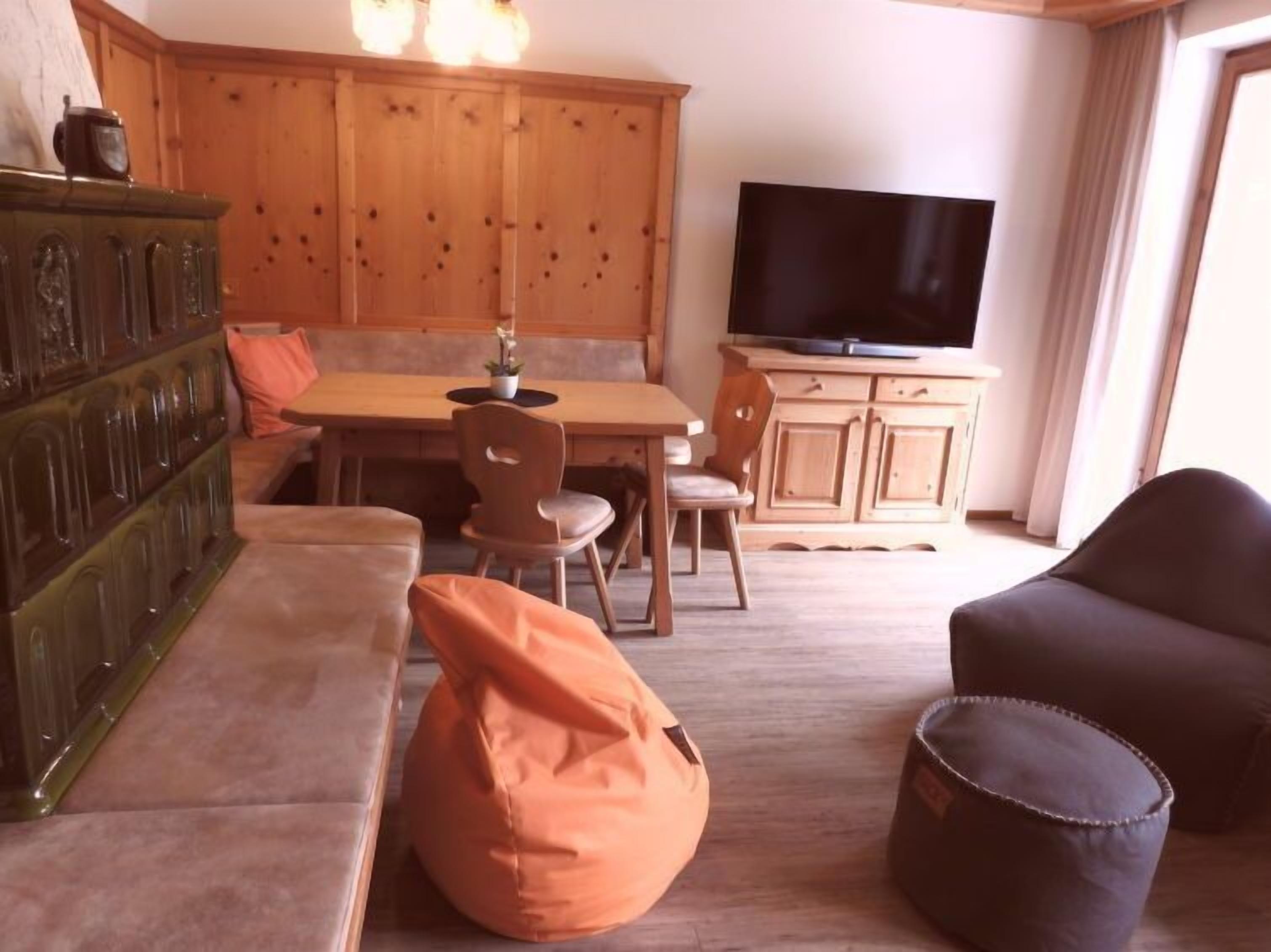 Una sala de estar acogedora con un sofá, un sillón de peluche, un televisor y armarios de madera.