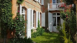 Un bâtiment de style européen traditionnel, doté d’une cour intérieure, d’un balcon avec des balustrades blanches et d’une façade en briques.