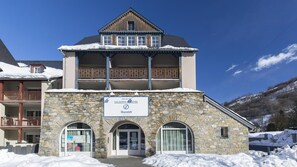 A two-story building with a stone facade, a balcony, and a sign indicating it is a vacation rental. - Wifi, 50m from resort center, sauna, jacuzzi, hammam, terrace, balcony, parking, tv, ski locker (Loudenvielle)