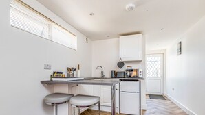 A compact kitchen with a built-in refrigerator, a microwave, and a toaster. There are two bar stools and a small countertop. - Charming Chalet A Stone's Throw From The Beach! - Pass the Keys (Chichester)