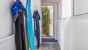 A hallway with surfboards on hooks, a radiator, and a door leading outside. - Charming Chalet A Stone's Throw From The Beach! - Pass the Keys (Chichester)