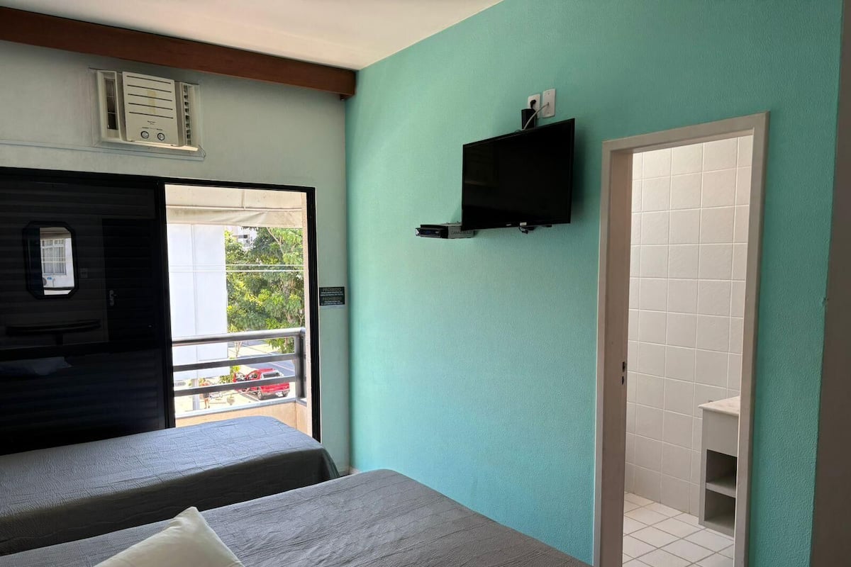 Una habitación con dos camas, televisión, ventana y puerta que da a un balcón.