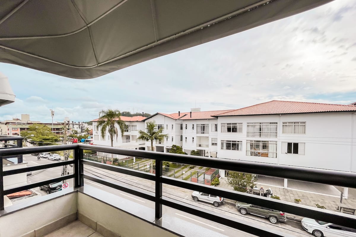 Un balcón con vista a una zona residencial, con edificios blancos de techos rojos y palmeras.