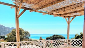 Une pergola en bois, dotée d’un toit en osier, offrant une vue imprenable sur la côte.