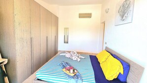 A bedroom with a bed, a wardrobe, a bedside table, and a wall-mounted air conditioner.