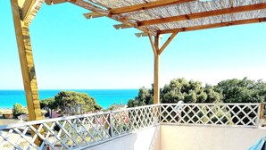 A wooden table and chairs on a balcony with a view of the sea.