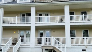 A two-story building with a covered front porch, a staircase leading to the entrance, and a small front yard.